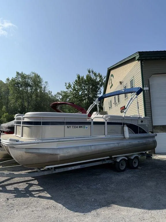 Slide: The Image of 2015 Bennington 21 SLX pontoon boat on trailer, parked near a building. - 1