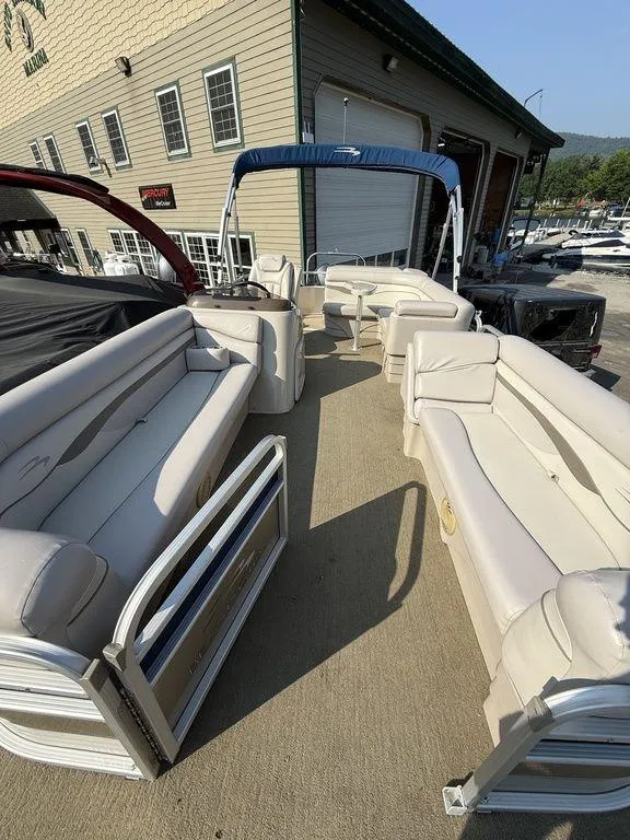 Slide: The Image of 2015 Bennington 21 SLX pontoon boat with spacious seating, docked near a marina building. - 10