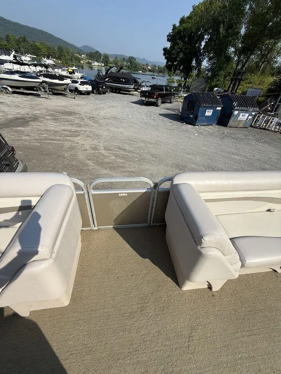 Slide: The Image of 2015 Bennington 21 SLX pontoon boat interior at a marina with parked boats and vehicles. - 15
