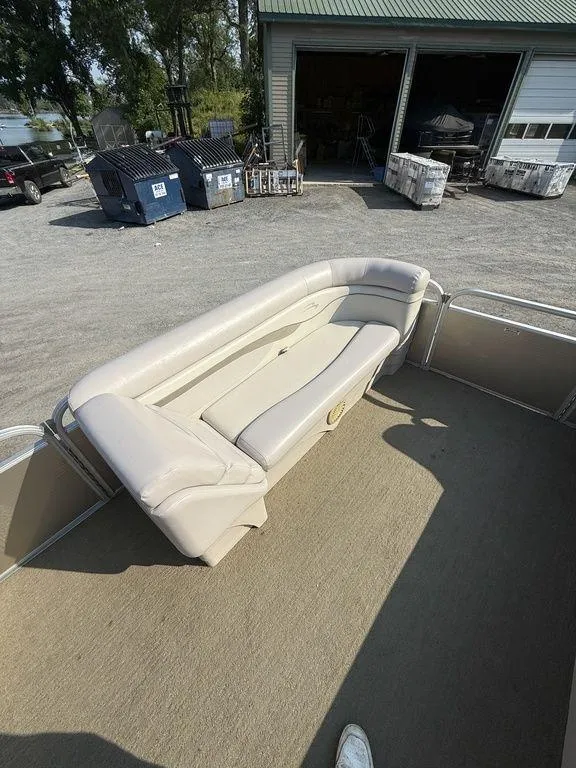 Slide: The Image of 2015 Bennington 21 SLX pontoon boat with beige seating, parked near a garage. - 19