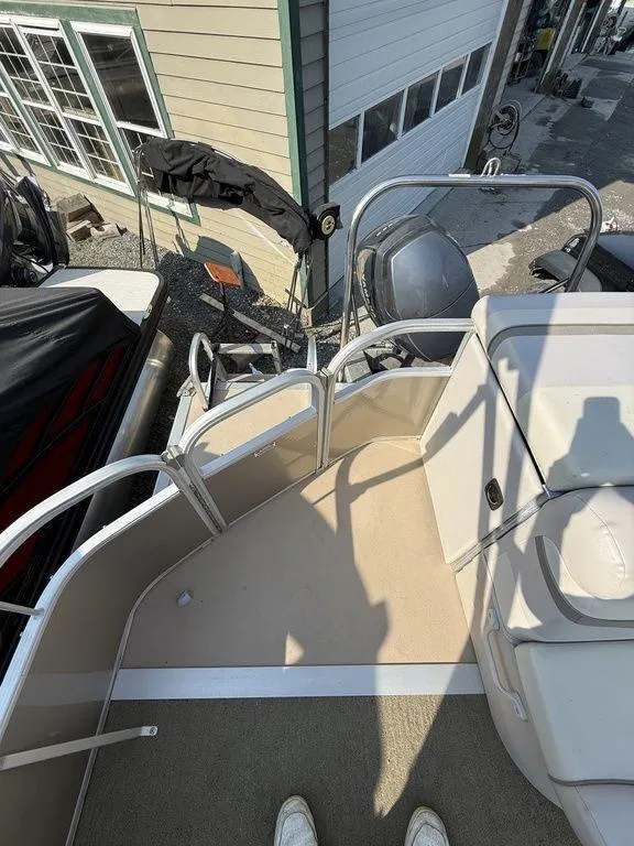 Slide: The Image of 2015 Bennington 21 SLX boat deck with railing and seating, parked near a building. - 23