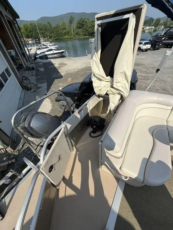 Slide: The Image of 2015 Bennington 21 SLX pontoon boat with seating, docked near a scenic waterfront. - 27