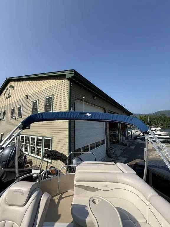 Slide: The Image of 2015 Bennington 21 SLX pontoon boat with blue canopy near a marina building. - 29