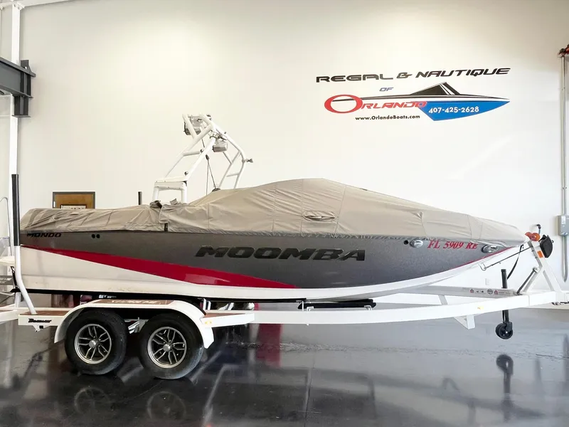 Slide: The Image of 2016 Moomba Mondo boat on trailer, covered, in showroom with branding on wall. - 3