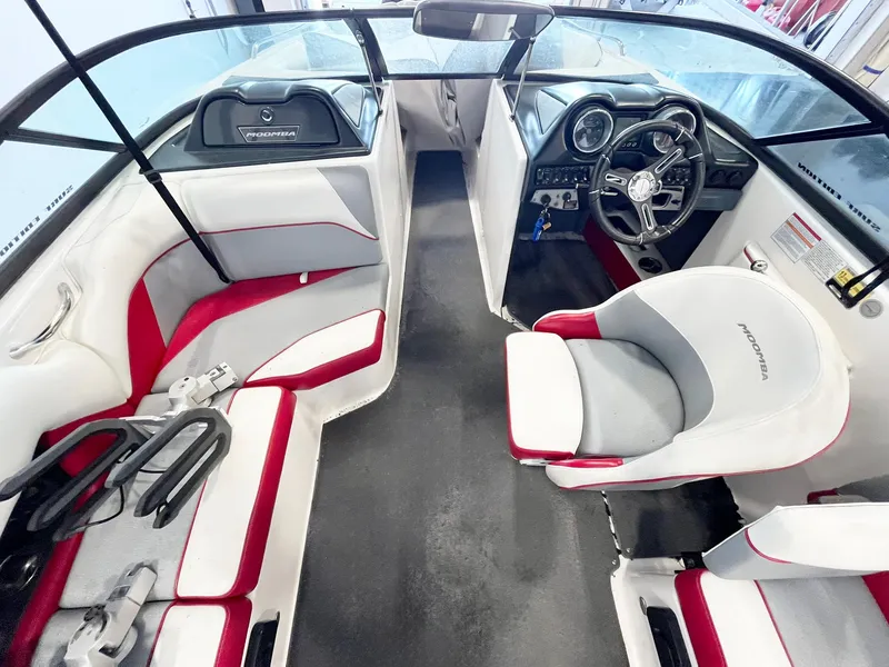 Slide: The Image of 2016 Moomba Mondo boat interior with red and white seating, steering wheel, and dashboard. - 9