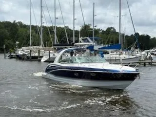 Slide: The Image of 2012 Formula 350 Sun Sport boat cruising near marina with sailboats in background. - 2