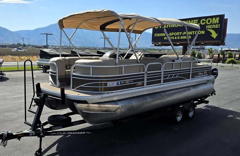 Slide: The Image of 2023 Sun Tracker SportFish 22 XP3 pontoon boat on trailer, outdoor setting. - 6