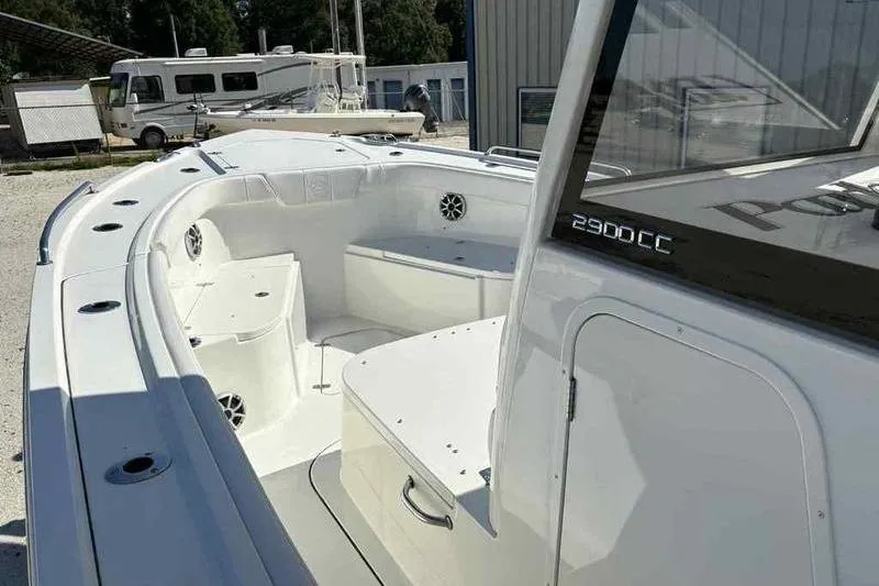 Slide: The Image of 2026 Parker 2900 CC boat interior with seating and storage, parked near RV and buildings. - 12