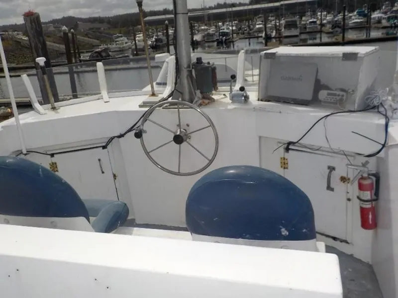 Slide: The Image of 1974 custom passenger vessel helm with steering wheel, blue seats, and marina background. - 2