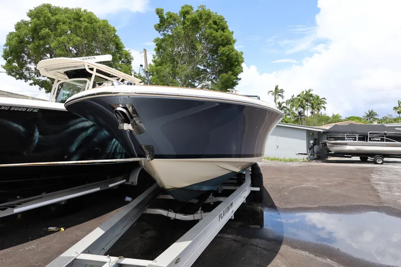 Slide: The Image of 2020 Chris-Craft 30 Launch boat on trailer, parked outdoors with trees and sky background. - 20
