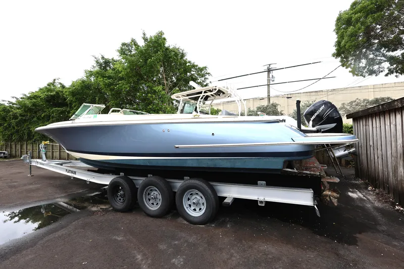 Slide: The Image of 2020 Chris-Craft 30 Launch boat on trailer, parked outdoors with trees in background. - 3