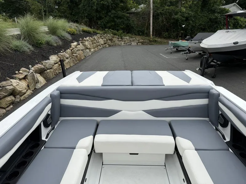 Slide: The Image of 2026 Axis A225 boat interior with gray and white seating, parked on a paved driveway. - 16
