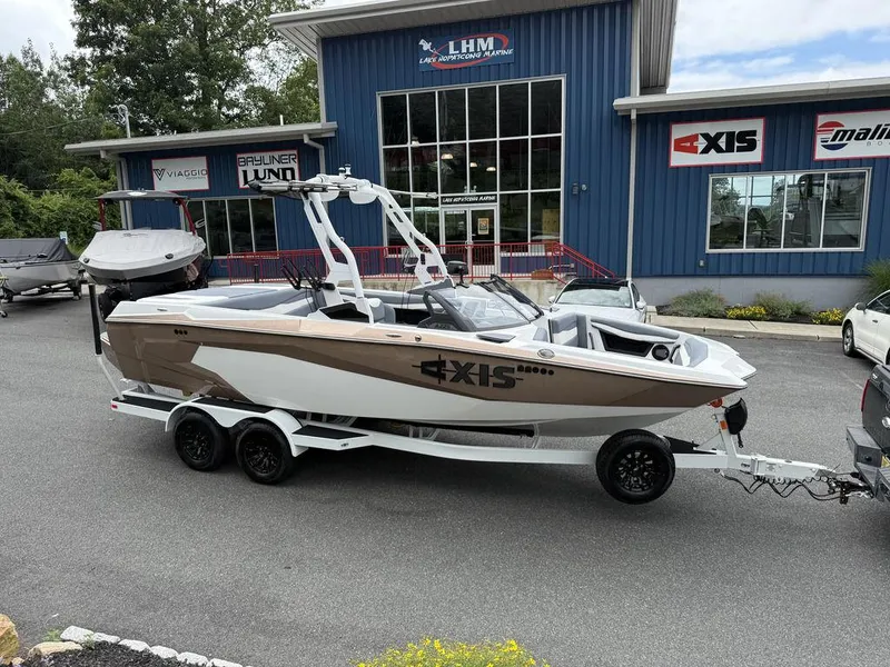 The Image of 2026 Axis A225 boat on trailer outside dealership, featuring sleek design and modern architecture. - 2