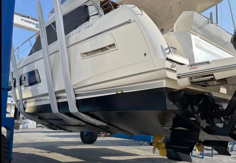 Slide: The Image of Prestige 460 yacht, 2020 model, in dry dock for maintenance, showcasing hull and propellers. - 40