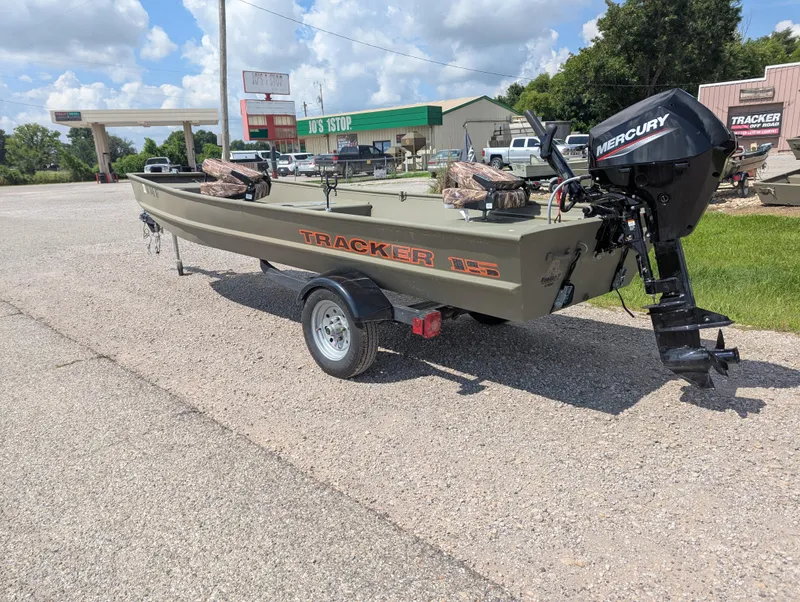 Slide: The Image of 2025 Tracker Grizzly 15 Jon boat with Mercury motor on trailer, parked outdoors. - 20