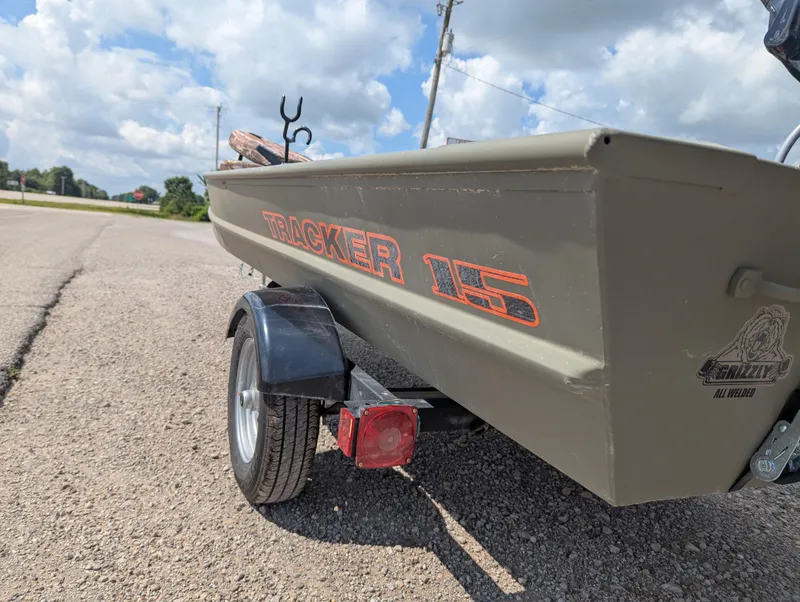Slide: The Image of 2025 Tracker Grizzly 15 Jon boat on trailer, parked on a sunny day. - 21