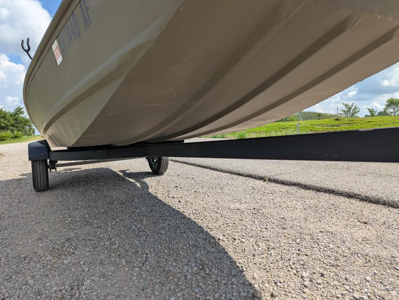 Slide: The Image of 2025 Tracker Grizzly 15 Jon boat on trailer, parked on gravel road. - 27