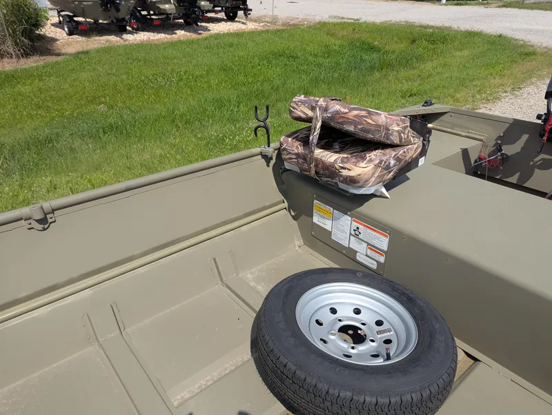 Slide: The Image of 2025 Tracker Grizzly 15 Jon boat interior with spare tire and camouflage cushions. - 32