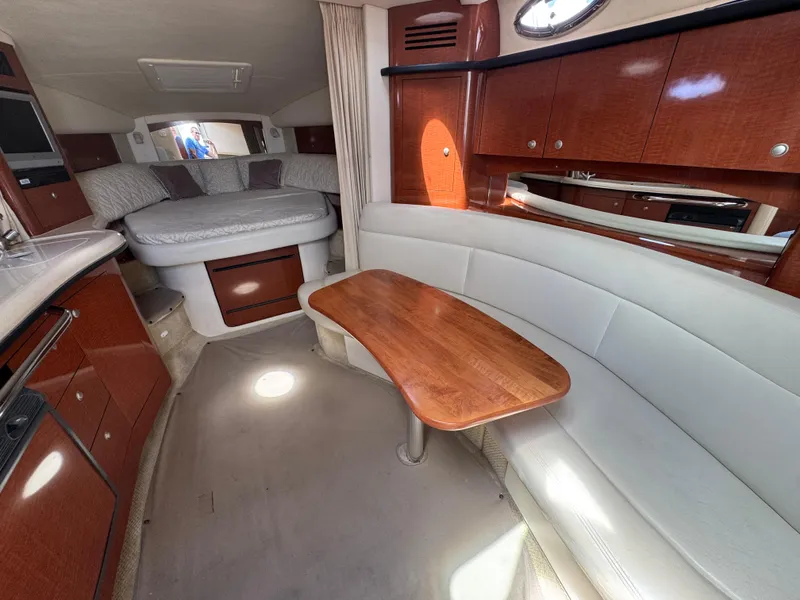 Slide: The Image of 2005 Sea Ray 320 Sundancer interior with wood cabinetry, dining area, and cozy sleeping quarters. - 11