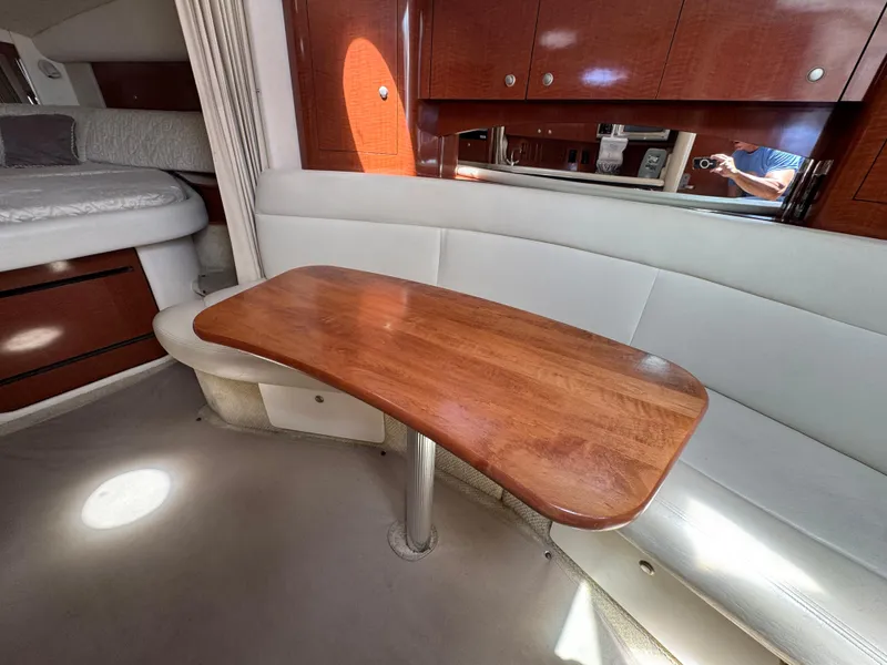 Slide: The Image of Interior of 2005 Sea Ray 320 Sundancer with wooden table and white seating. - 12