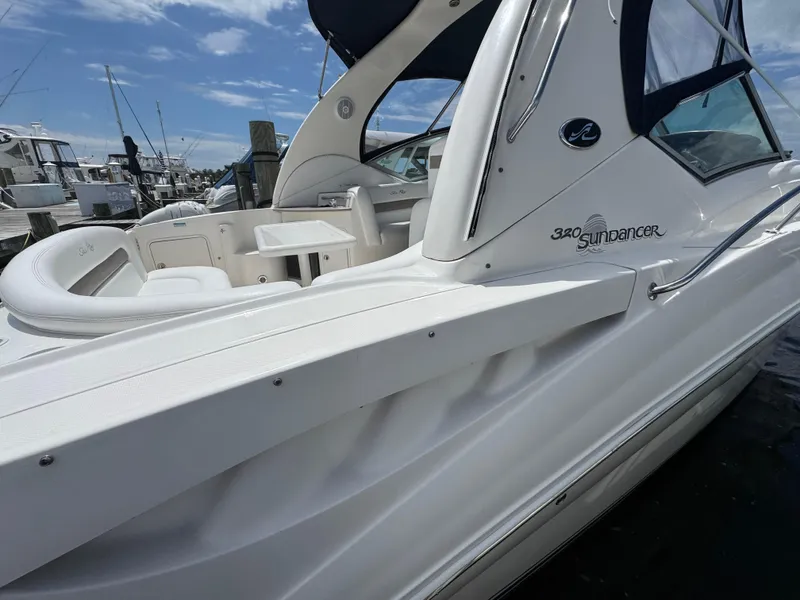 Slide: The Image of 2005 Sea Ray 320 Sundancer boat docked, showcasing sleek design and spacious seating area. - 3