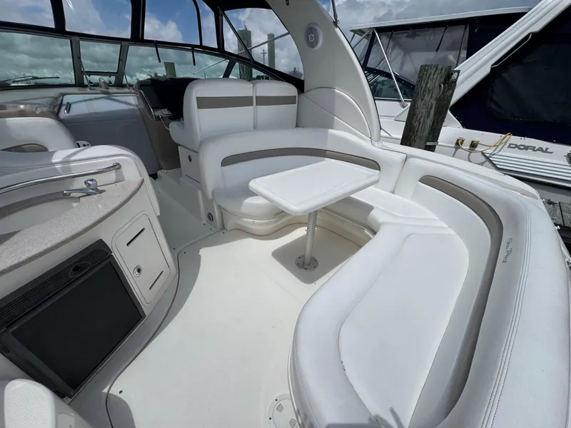 Slide: The Image of 2005 Sea Ray 320 Sundancer interior with white seating and table, docked at marina. - 4