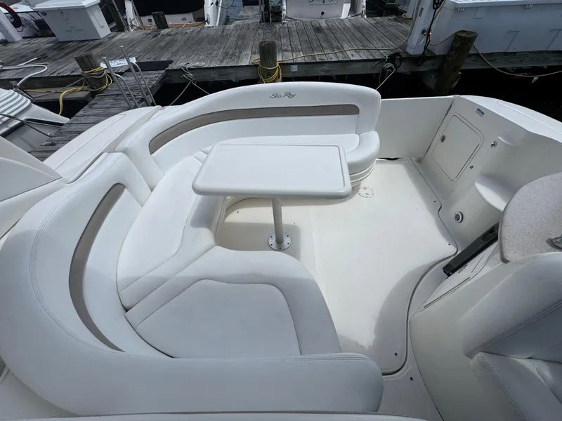 Slide: The Image of 2005 Sea Ray 320 Sundancer cockpit with white seating and table, docked at marina. - 5