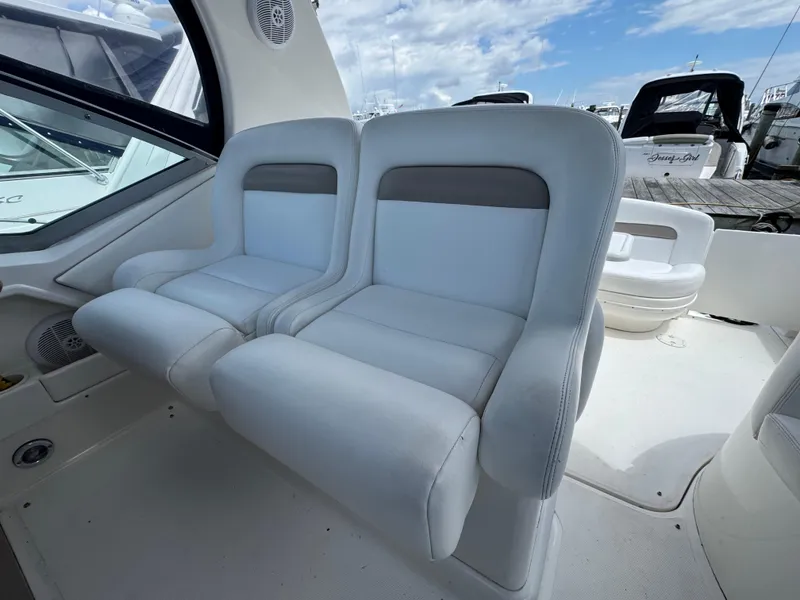 Slide: The Image of 2005 Sea Ray 320 Sundancer interior with white cushioned seating and marina view. - 7