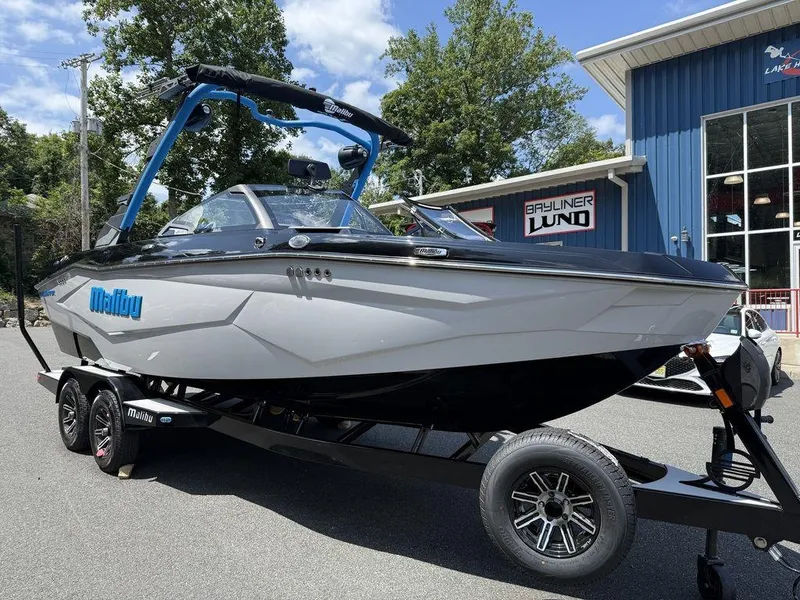 Slide: The Image of 2026 Malibu 22 LSV boat on trailer, parked outside dealership, sunny day. - 11