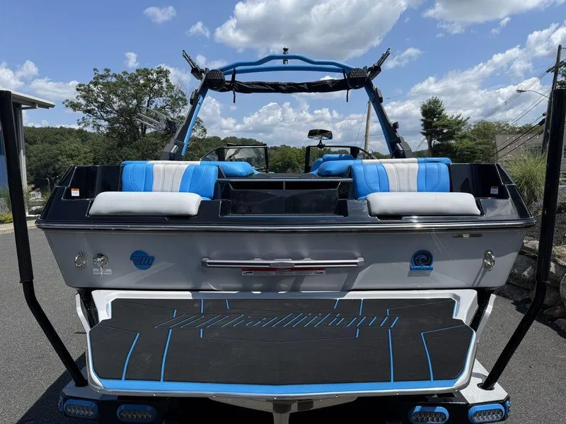 Slide: The Image of 2026 Malibu 22 LSV boat with blue and white seating, parked outdoors under a cloudy sky. - 12