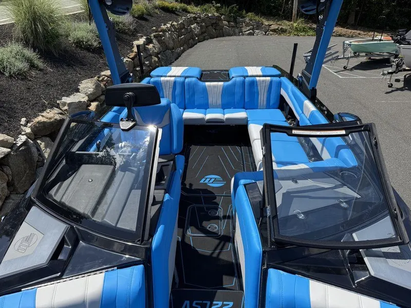 Slide: The Image of 2026 Malibu 22 LSV boat interior with blue and white seating, parked outdoors. - 14