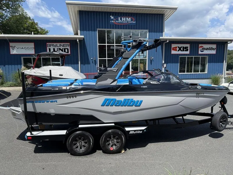 Slide: The Image of 2026 Malibu 22 LSV boat on trailer outside dealership, featuring sleek design and blue accents. - 4