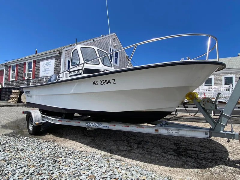 Slide: The Image of 1999 Maritime Skiff 20D boat on trailer at marina, clear blue sky background. - 1