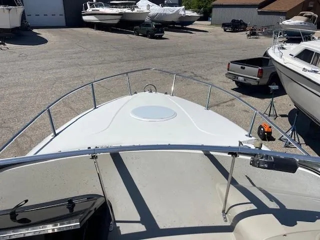 Slide: The Image of 1999 Four Winns 258 Vista boat in a marina, surrounded by other boats and vehicles. - 10