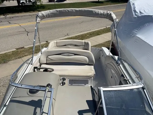 Slide: The Image of 1999 Four Winns 258 Vista boat interior with seating and steering wheel, parked on roadside. - 12