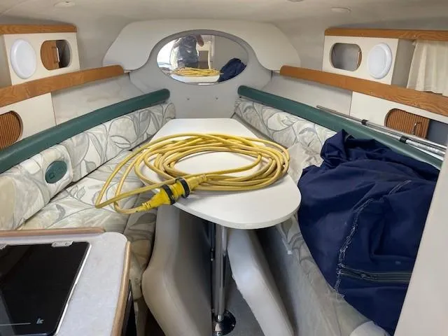 Slide: The Image of Interior of 1999 Four Winns 258 Vista boat with seating, table, and coiled yellow cable. - 15
