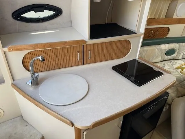 Slide: The Image of Compact kitchenette in 1999 Four Winns 258 Vista boat with sink, stove, and storage. - 16