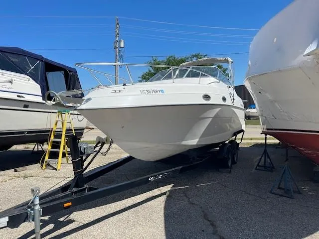 Slide: The Image of 1999 Four Winns 258 Vista boat on trailer, parked outdoors under clear blue sky. - 3