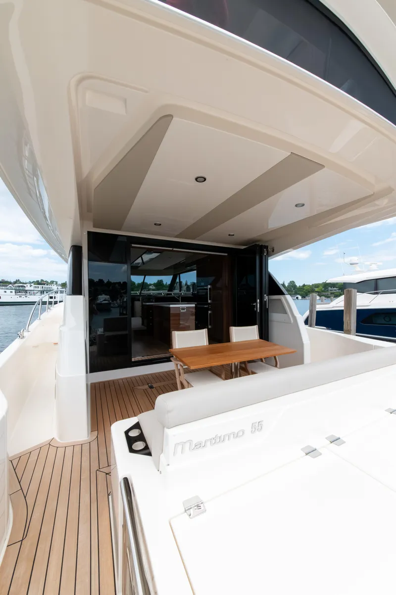 Slide: The Image of 2024 Maritimo M55 yacht deck with seating and table, docked at marina. - 13