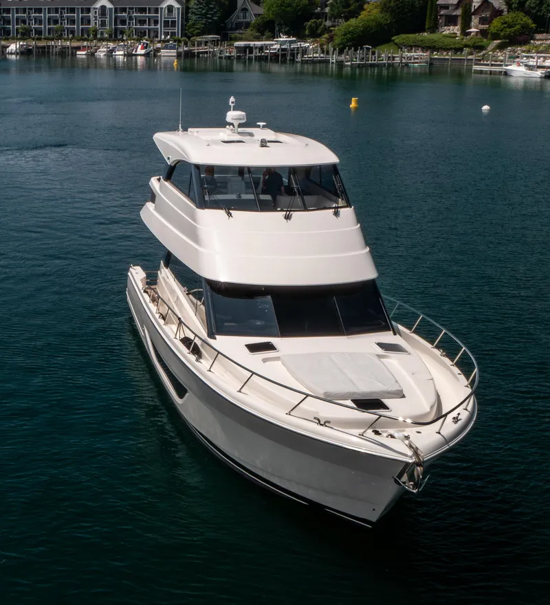 Slide: The Image of 2024 Maritimo M55 yacht cruising on a serene lake near a marina. - 5