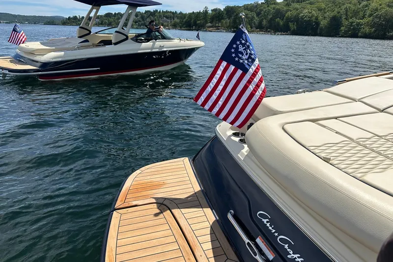 Slide: The Image of 2026 Chris-Craft Sportster 28 boats on a lake, featuring American flags. - 10
