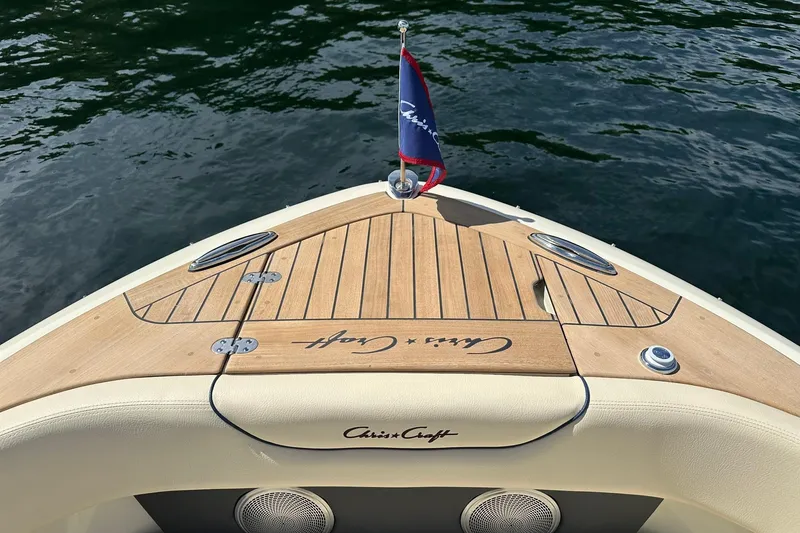 Slide: The Image of 2026 Chris-Craft Sportster 28 boat with teak deck and flag on calm water. - 22