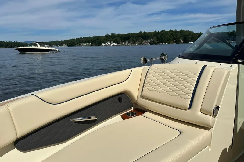 Slide: The Image of 2026 Chris-Craft Sportster 28 boat interior with beige seating on a lake. - 24