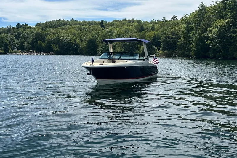 Slide: The Image of 2026 Chris-Craft Sportster 28 boat on a serene lake with lush green forest backdrop. - 3