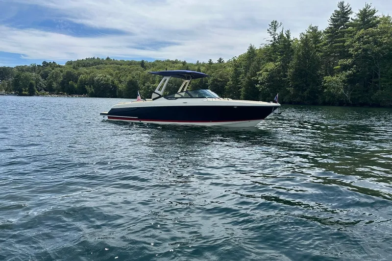 Slide: The Image of 2026 Chris-Craft Sportster 28 boat on a serene lake with lush green trees. - 5