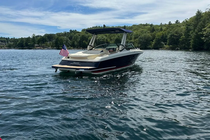 Slide: The Image of 2026 Chris-Craft Sportster 28 boat on a serene lake with lush green shoreline. - 7