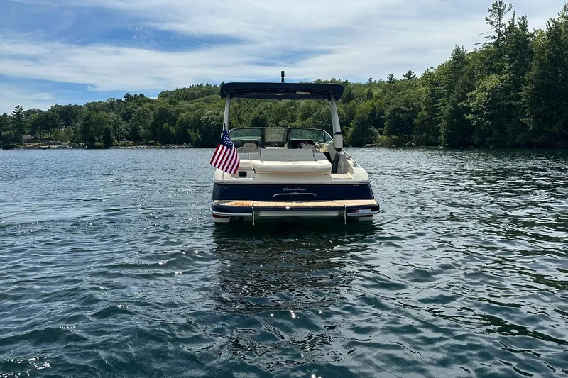 Slide: The Image of 2026 Chris-Craft Sportster 28 boat on a serene lake with lush green trees. - 8