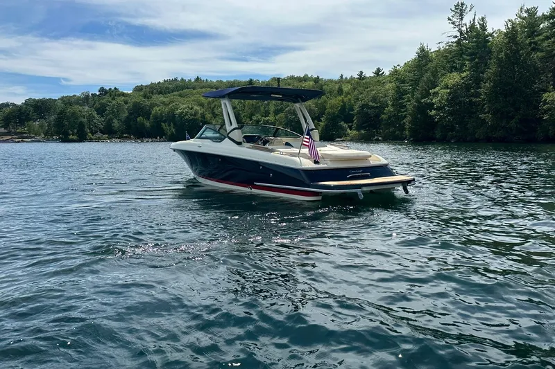 Slide: The Image of 2026 Chris-Craft Sportster 28 boat on a serene lake with lush green surroundings. - 9