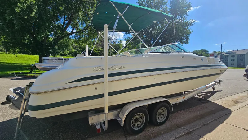 Slide: The Image of 2000 Chris-Craft 262 Sport Deck boat on trailer, parked outdoors with green canopy. - 3