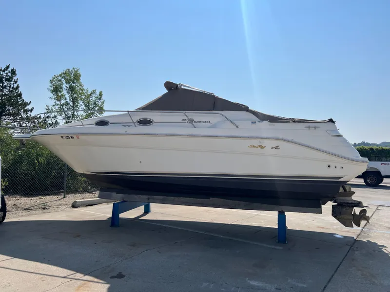 Slide: The Image of 1997 Sea Ray 270 Sundancer boat interior with steering wheel and seating, near a scenic waterfront. - 2